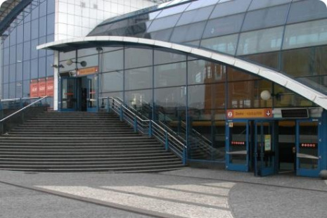 Celkový pohled na vstup do vestibulu a nástupiště metra v části stanice směrem od centra. Druhý vstup je zrcadlově umístěn na druhém konci stanice metra.